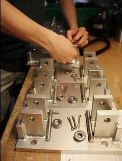 Technician building load cell mounting assemblies for a system