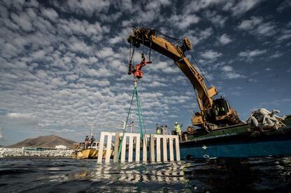 Crane lifting crate pallet out of sea water